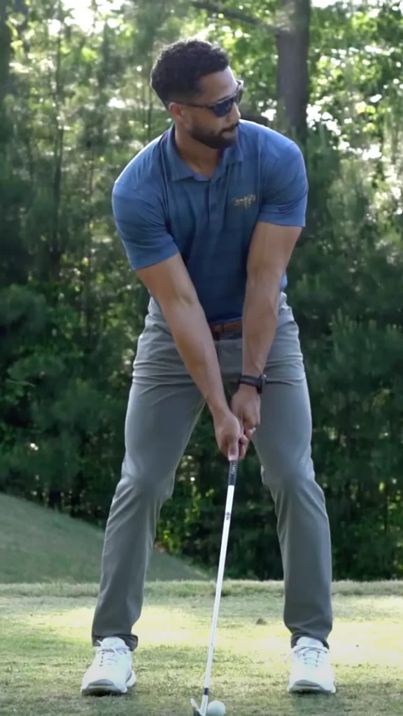 A man in a blue shirt and gray pants is golfing.