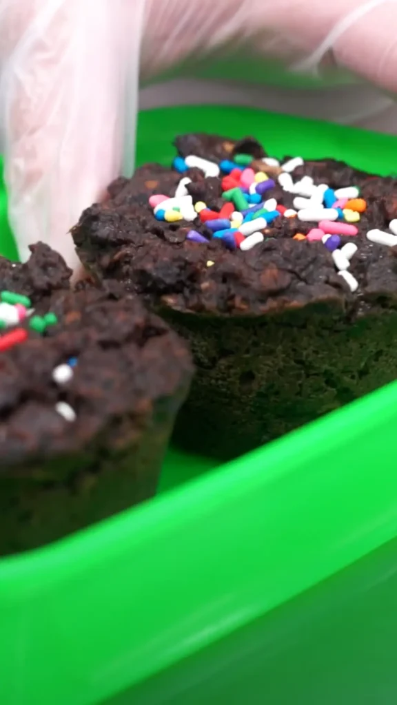 A close-up of chocolate cupcakes with rainbow sprinkles.