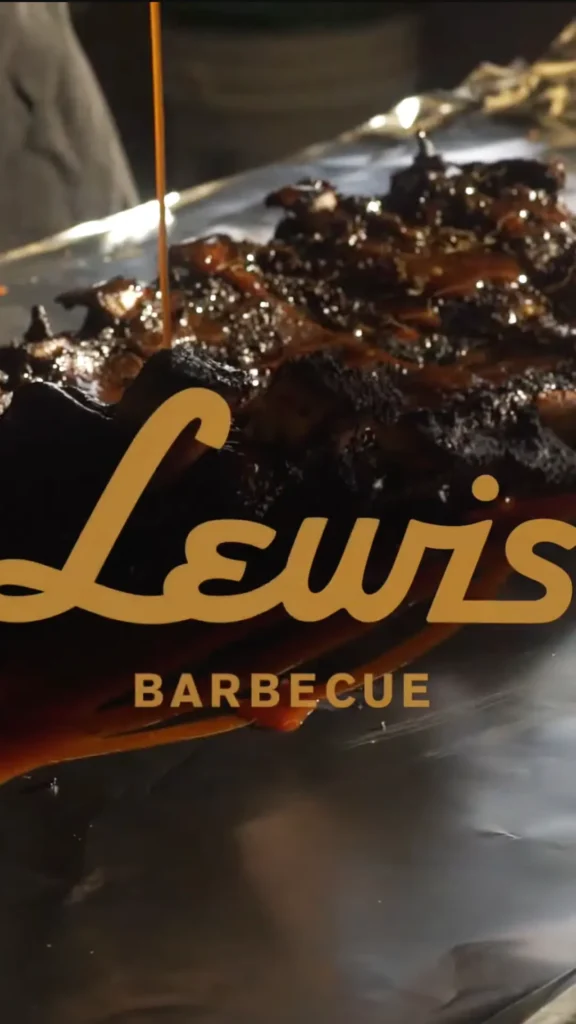 Meat being sauced with Lewis Barbeque logo.