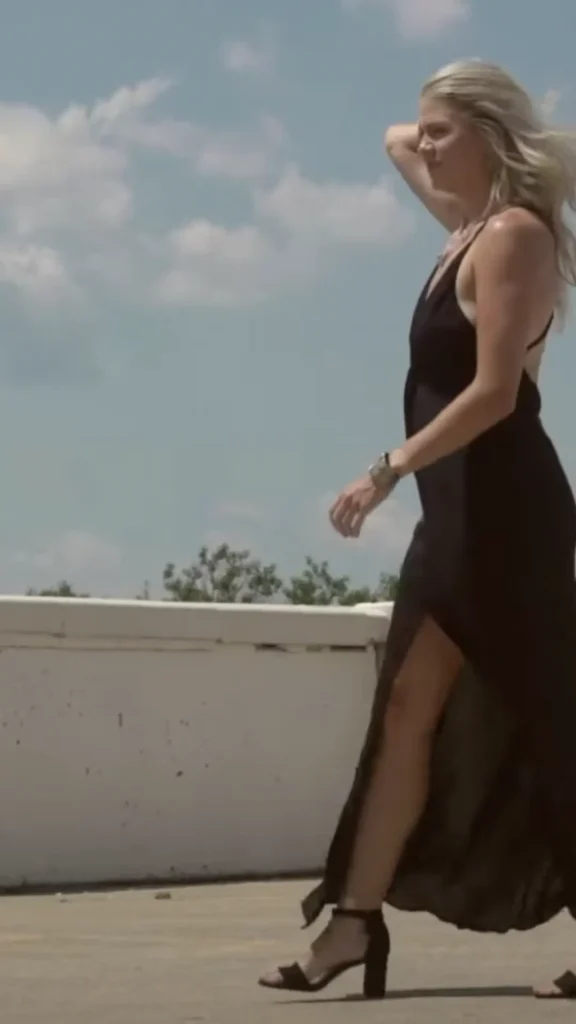 A woman in a black dress walking on a rooftop.