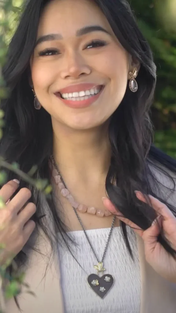 Smiling woman wearing a pink quartz necklace and earrings.